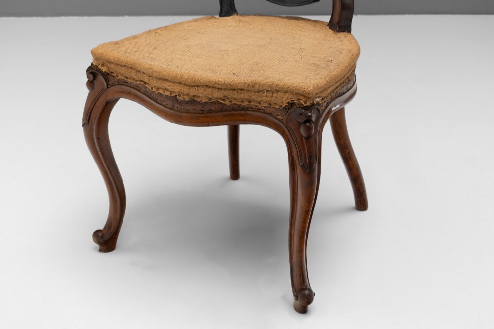 A pair of antique Victorian Rococo Revival carved timber side chairs with balloon backs, open scrollwork splats, cabriole legs, and neutral upholstery. View V