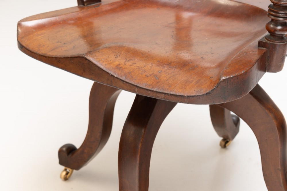 An antique Victorian swivel desk chair featuring a deep-buttoned dark leather backrest, shaped wooden seat, turned arm supports, and splayed legs on brass castors. View VIII