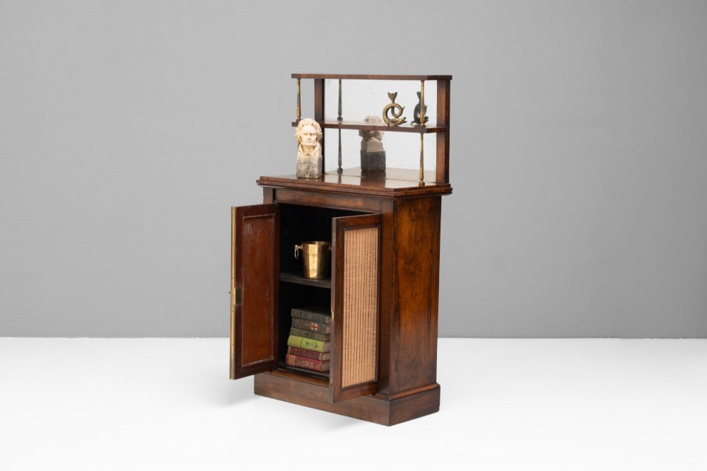 An antique rosewood chiffonier featuring a two-tier mirrored shelf superstructure supported by brass columns over a double-door cupboard with fabric panels. View III