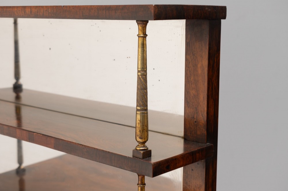 An antique rosewood chiffonier featuring a two-tier mirrored shelf superstructure supported by brass columns over a double-door cupboard with fabric panels. View V