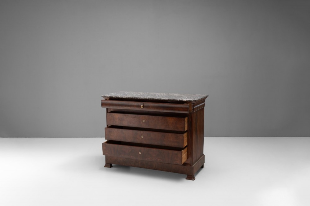 A nineteenth-century French mahogany commode featuring three main drawers, a grey marble top, and brass keyhole escutcheons. View II