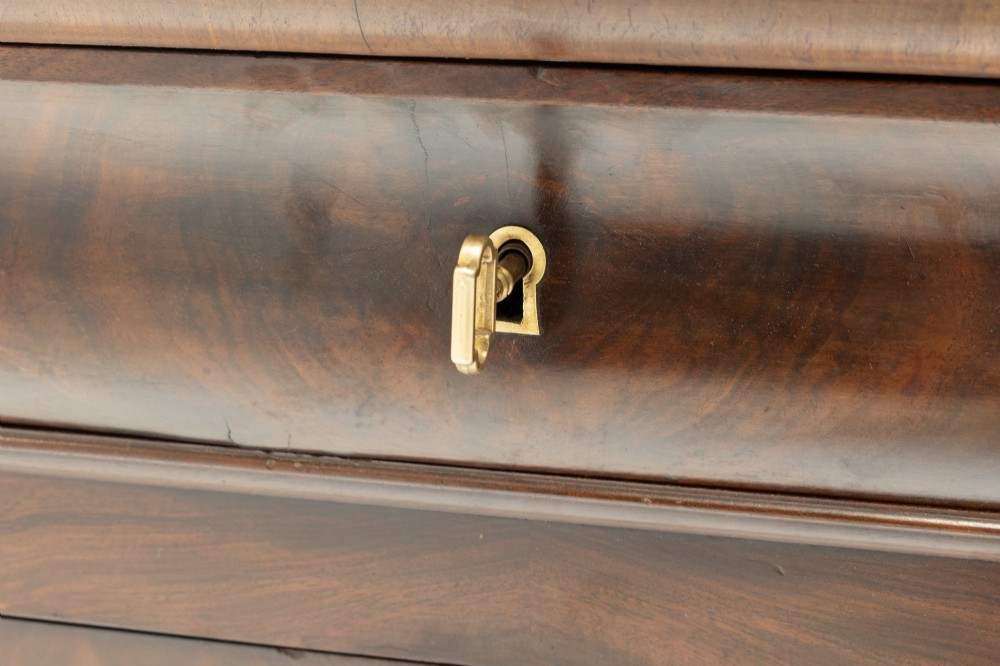 A nineteenth-century French mahogany commode featuring three main drawers, a grey marble top, and brass keyhole escutcheons. View IV