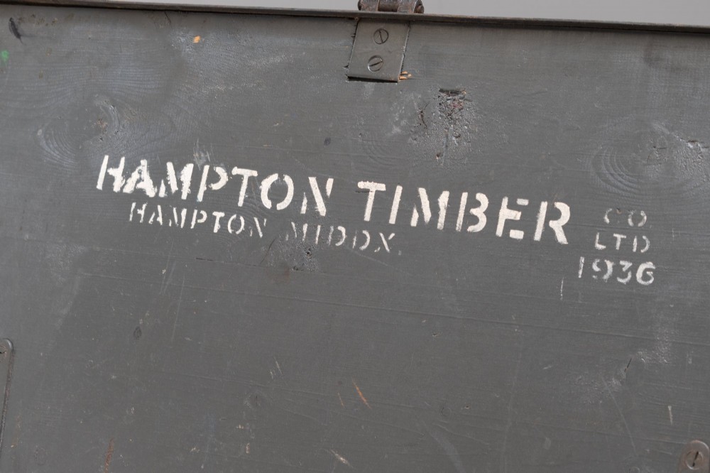 A dark brown rectangular wooden sea chest featuring white painted lettering on the flat lid and iron drop side handles. View IV