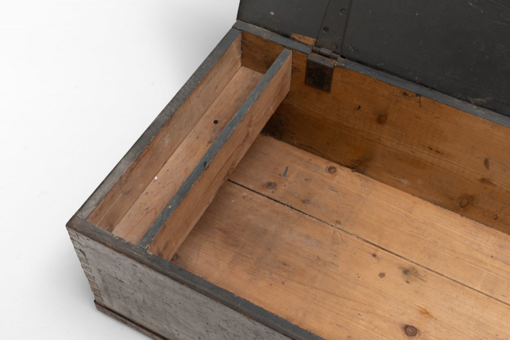 A dark brown rectangular wooden sea chest featuring white painted lettering on the flat lid and iron drop side handles. View VI