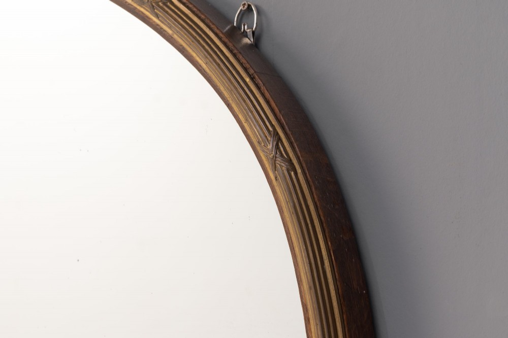 A wide arched overmantel mirror featuring a reeded gilt frame with detailed cross-ribbon motifs and a flat wooden base. View II