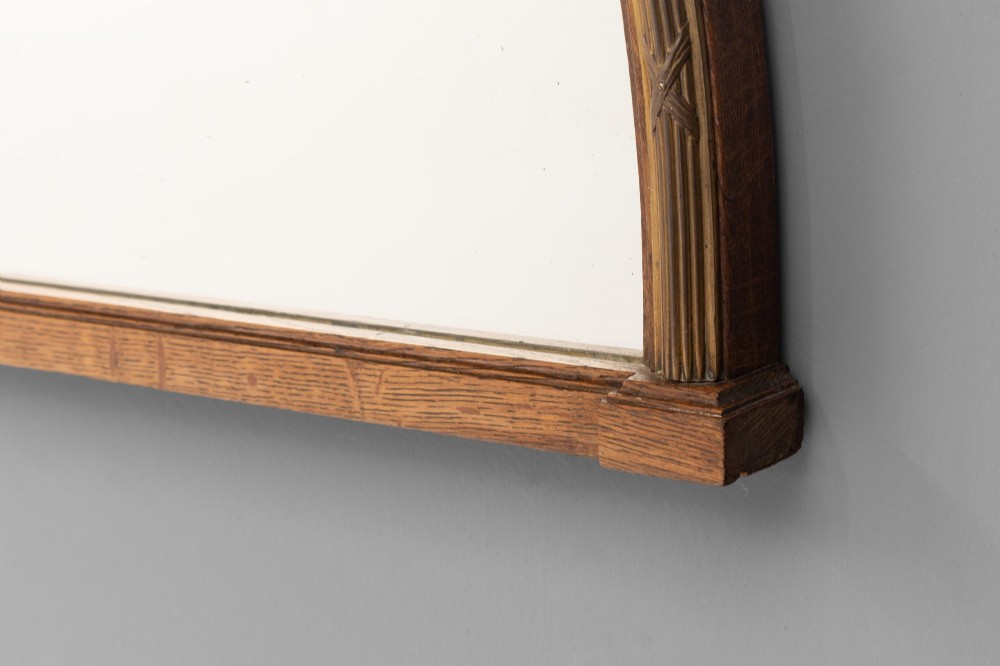 A wide arched overmantel mirror featuring a reeded gilt frame with detailed cross-ribbon motifs and a flat wooden base. View III