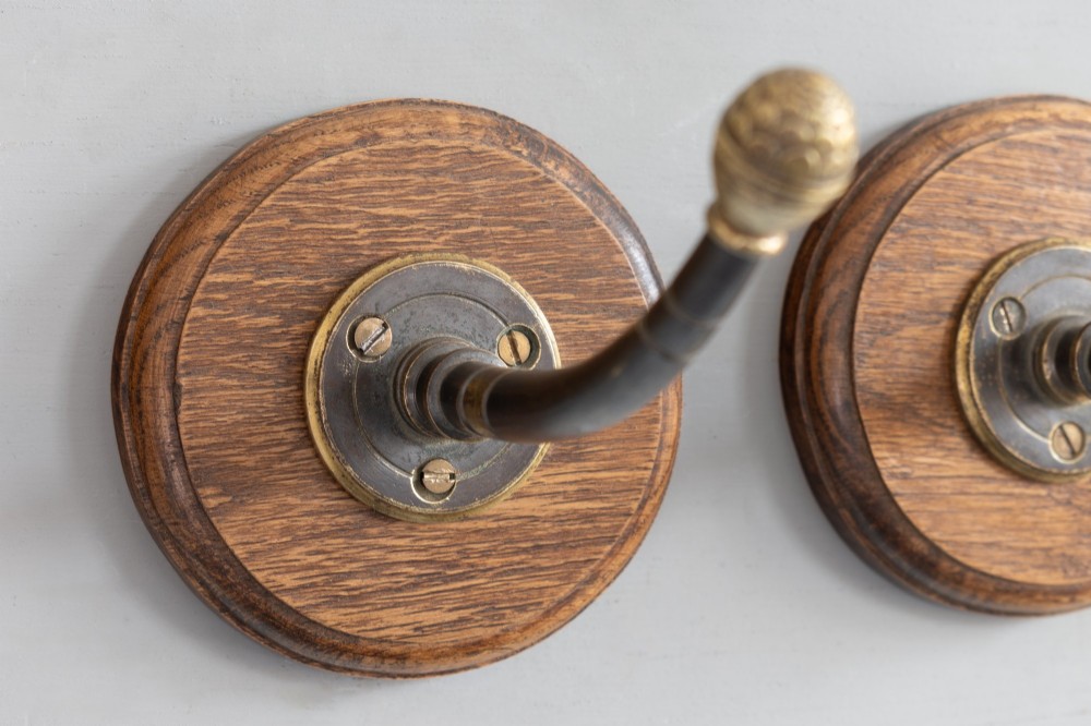 A set of four circular turned oak backplates each mounted with a central cast brass coat hook. View III