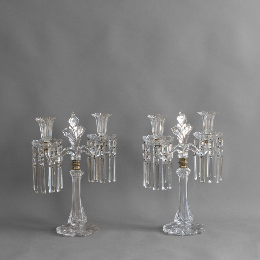 A pair of clear cut glass two-arm candelabras featuring hanging prism drops, fluted stems, and scalloped bases.