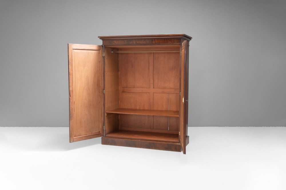 A nineteenth-century two-door flame mahogany cupboard with arched panelled doors and a moulded top cornice. View II