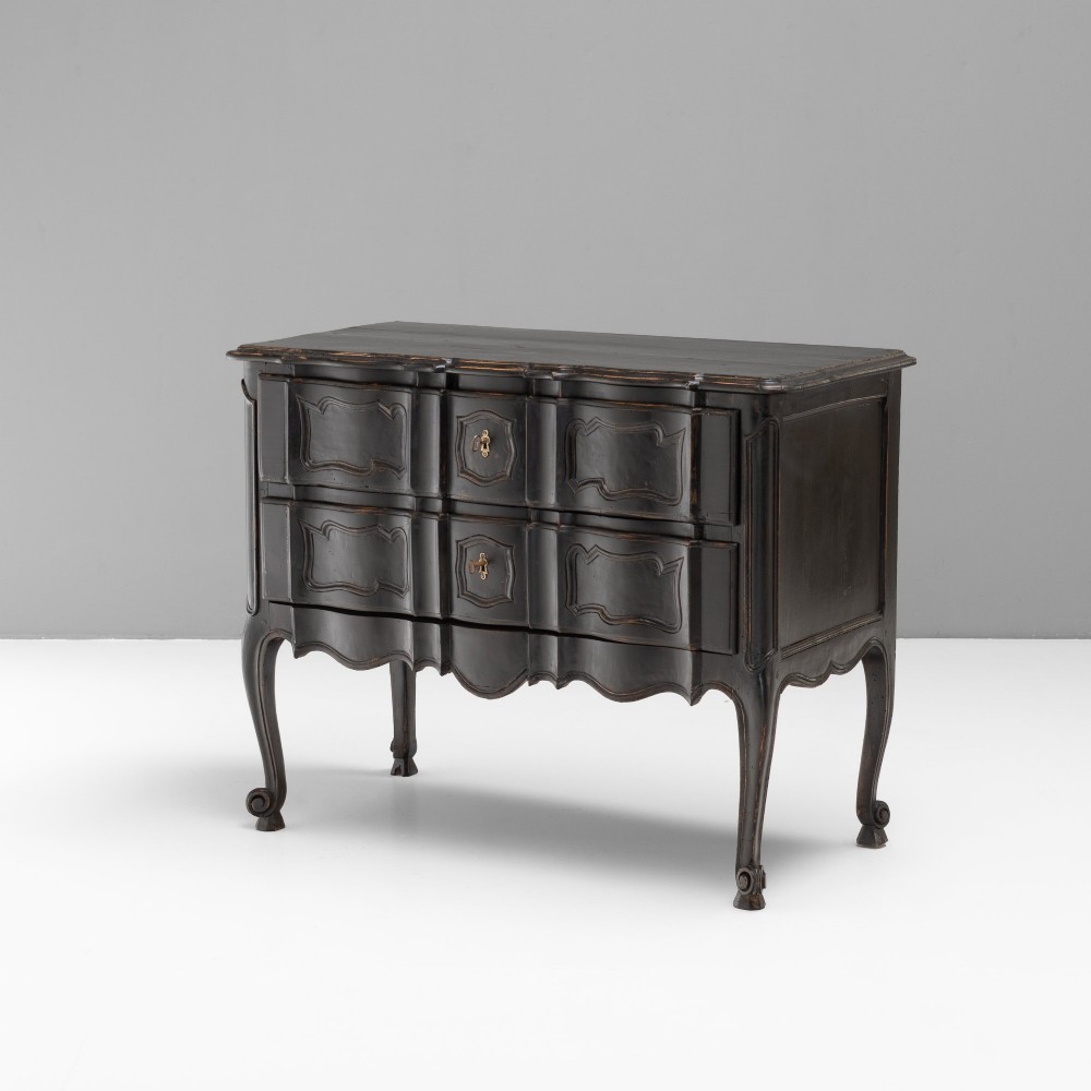 An antique dark brown painted French Rococo style commode featuring serpentine drawer fronts, cabriole legs, moulded panel details, and central brass key escutcheons. View II