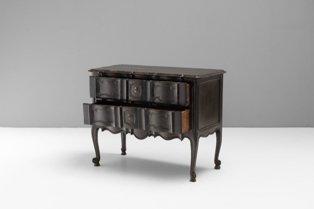 An antique dark brown painted French Rococo style commode featuring serpentine drawer fronts, cabriole legs, moulded panel details, and central brass key escutcheons. View IV