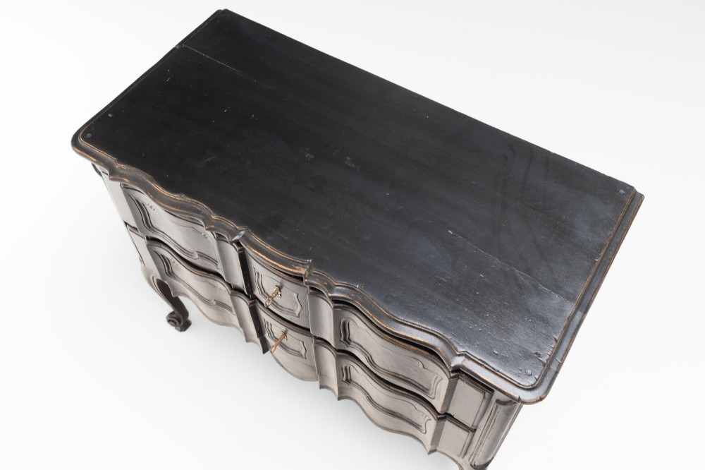 An antique dark brown painted French Rococo style commode featuring serpentine drawer fronts, cabriole legs, moulded panel details, and central brass key escutcheons. View V