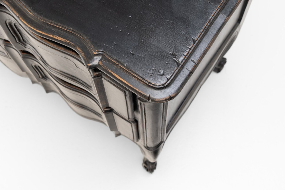 An antique dark brown painted French Rococo style commode featuring serpentine drawer fronts, cabriole legs, moulded panel details, and central brass key escutcheons. View VI