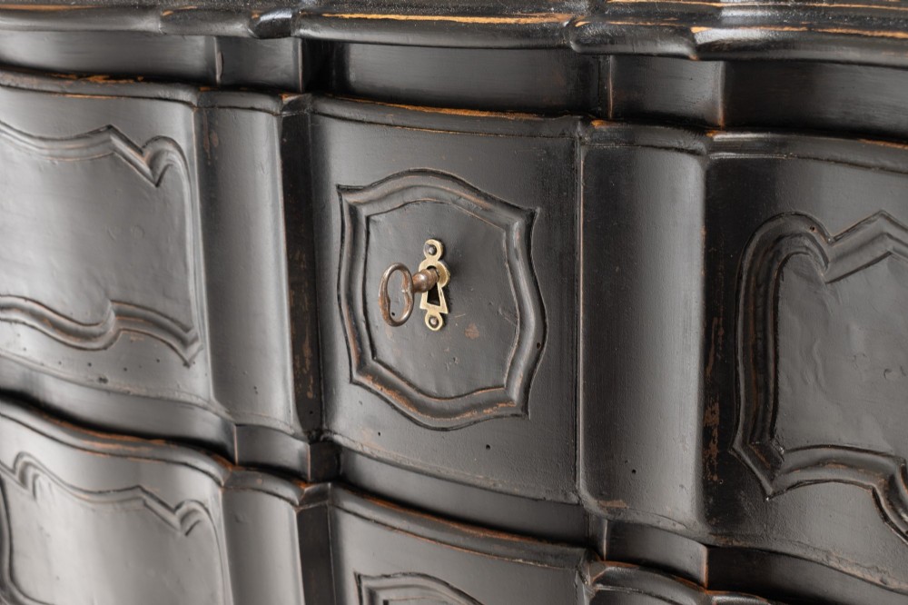 An antique dark brown painted French Rococo style commode featuring serpentine drawer fronts, cabriole legs, moulded panel details, and central brass key escutcheons. View VII