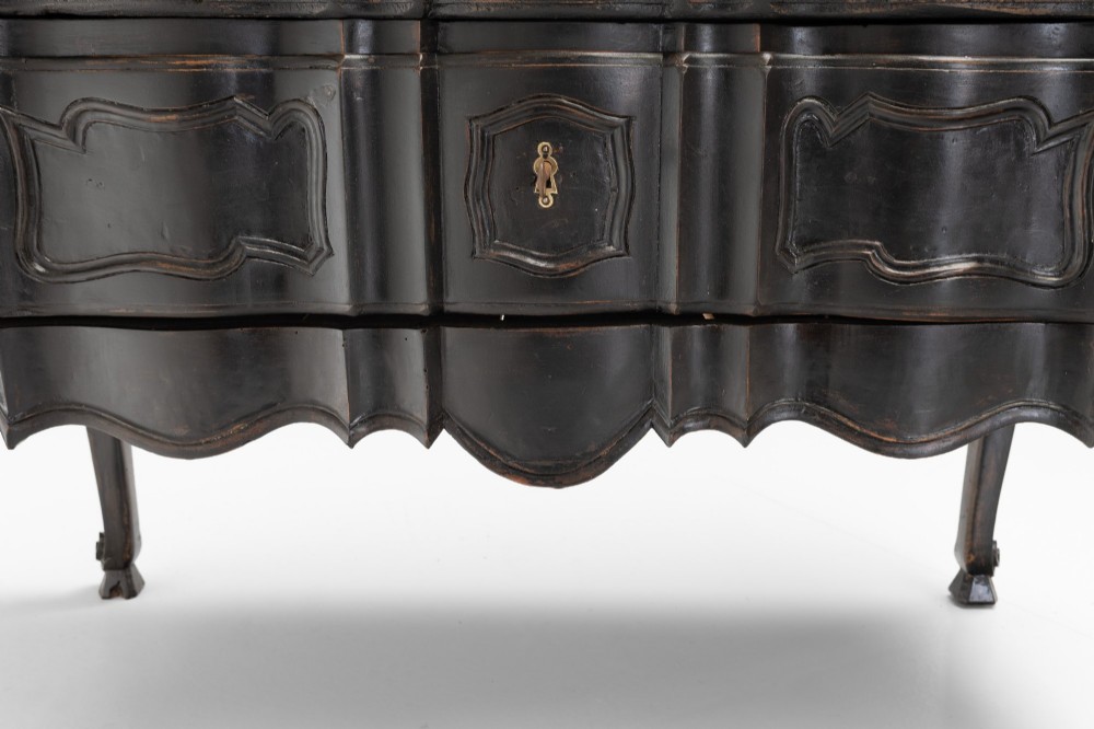 An antique dark brown painted French Rococo style commode featuring serpentine drawer fronts, cabriole legs, moulded panel details, and central brass key escutcheons. View IX