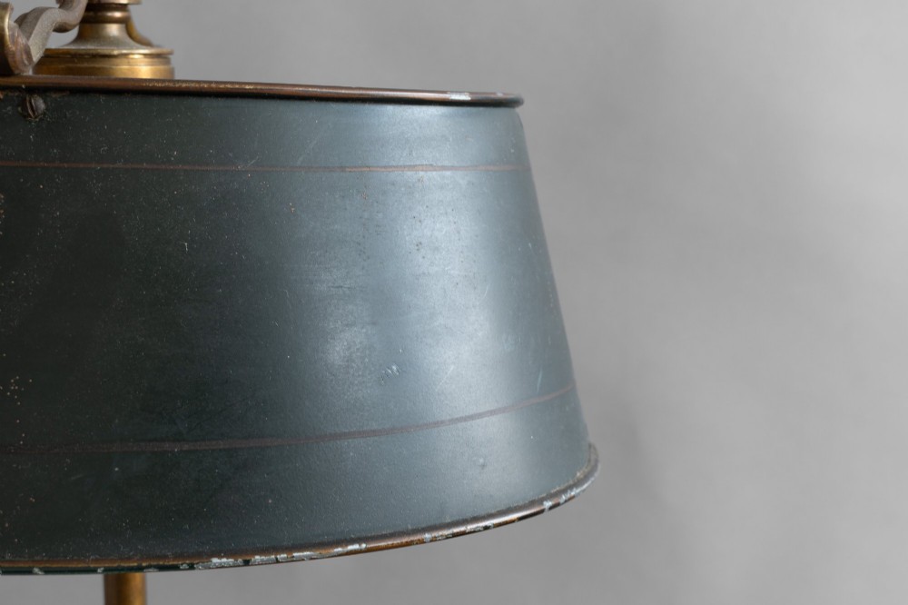 An antique French bouillotte lamp featuring a dark green metal tole shade, twin brass candle sconces, a central adjustment rod with a ring top, and a pierced dish base. View VIII