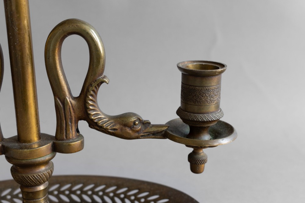 An antique French bouillotte lamp featuring a dark green metal tole shade, twin brass candle sconces, a central adjustment rod with a ring top, and a pierced dish base. View X