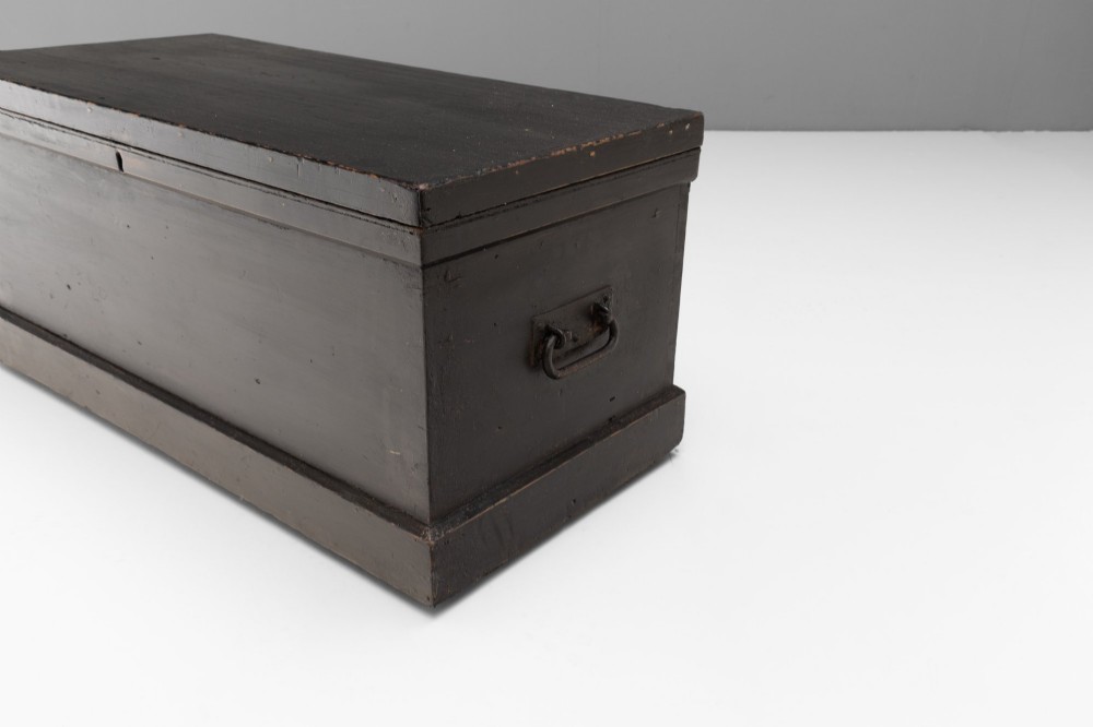 A dark painted rectangular pine storage trunk featuring an open hinged lid, natural pine interior, and iron side handles. View V