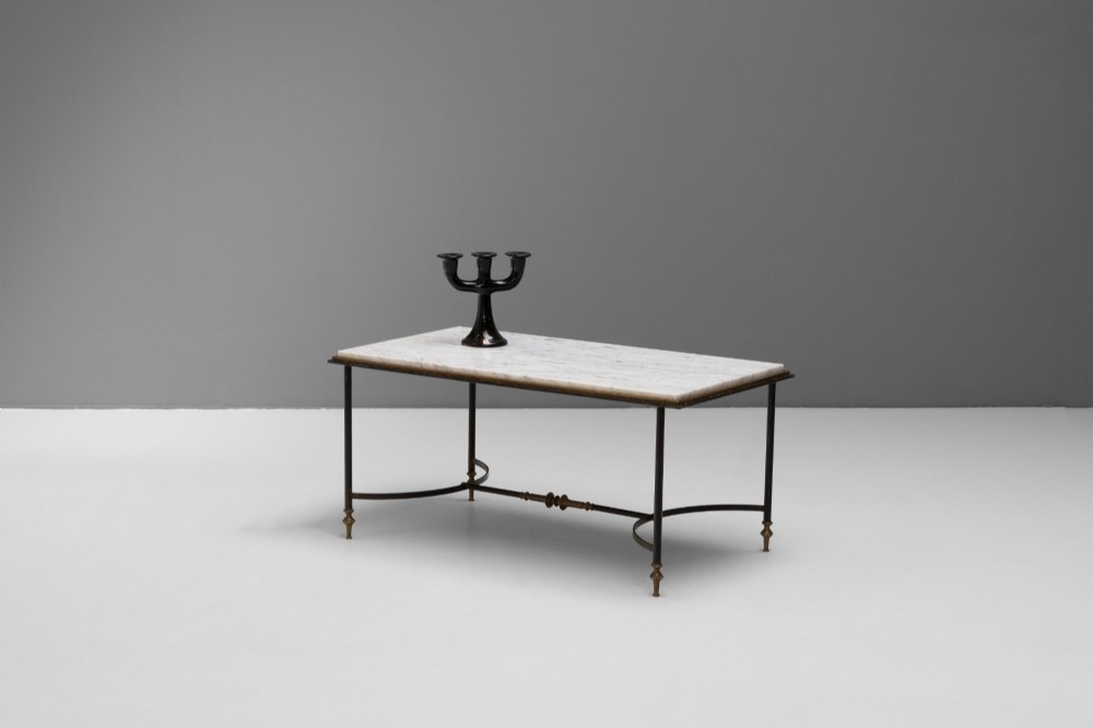 A rectangular coffee table featuring a polished white marble top set upon a black wrought iron frame with curved stretchers and brass finial feet.
