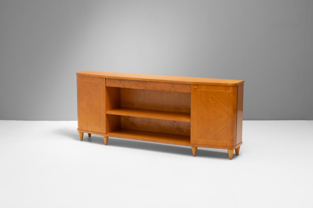 A Swedish Grace birch sideboard featuring chevron parquetry veneer doors, open central shelving, and tapered fluted feet. View III