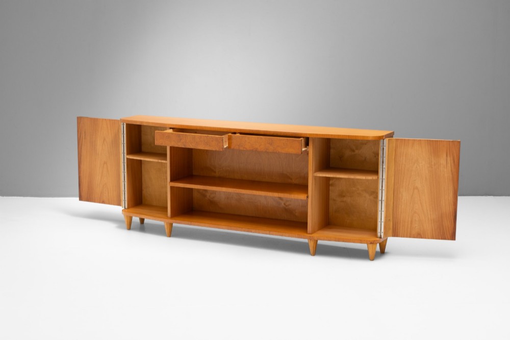 A Swedish Grace birch sideboard featuring chevron parquetry veneer doors, open central shelving, and tapered fluted feet. View IV