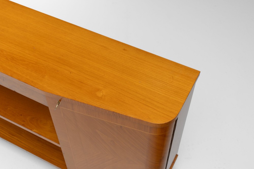 A Swedish Grace birch sideboard featuring chevron parquetry veneer doors, open central shelving, and tapered fluted feet. View VI