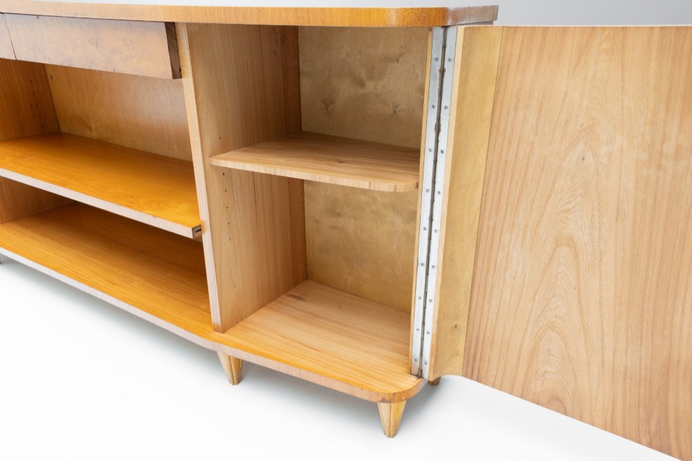 A Swedish Grace birch sideboard featuring chevron parquetry veneer doors, open central shelving, and tapered fluted feet. View VIII