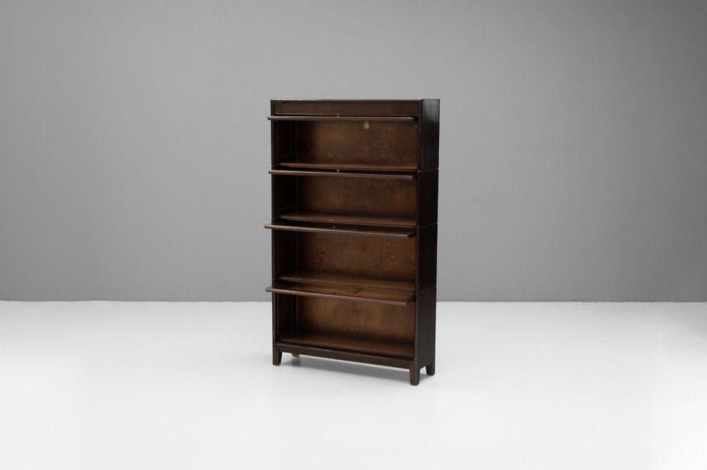 A four-tier dark wood sectional bookcase featuring glazed lift-and-slide doors with central brass knobs. View III