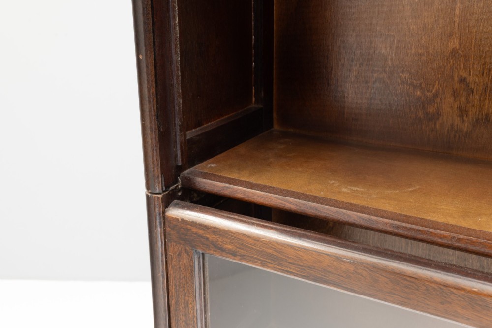 A four-tier dark wood sectional bookcase featuring glazed lift-and-slide doors with central brass knobs. View IX