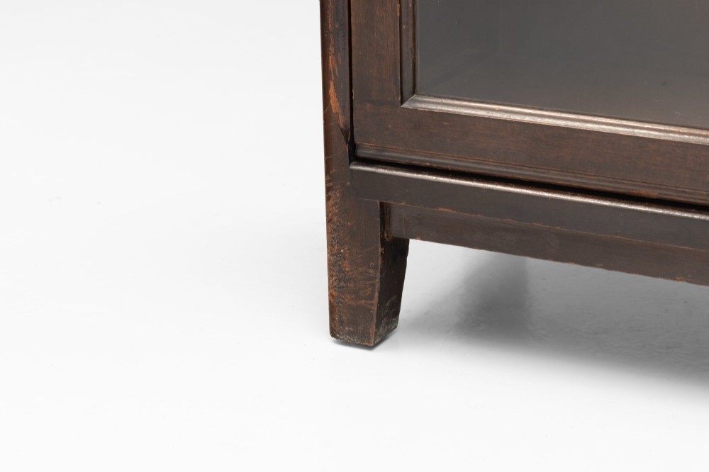 A four-tier dark wood sectional bookcase featuring glazed lift-and-slide doors with central brass knobs. View X