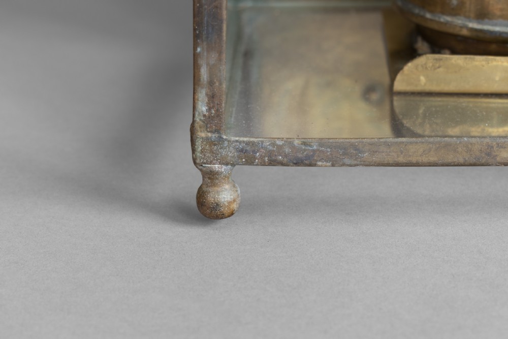 An antique glazed brass and copper lantern housing an internal glass oil lamp chimney and burner against a polished backplate. View VIII