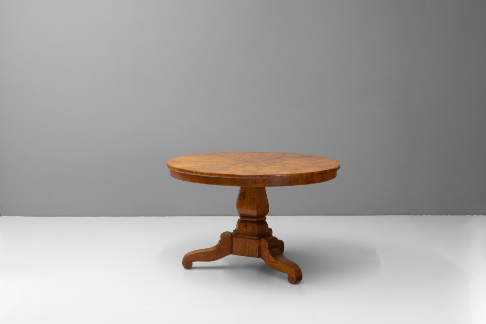 A Victorian tilt-top centre table in golden burr walnut veneer featuring a central starburst inlay and carved tripod pedestal base. View III