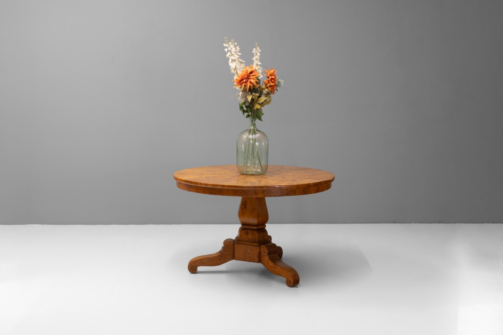 A Victorian tilt-top centre table in golden burr walnut veneer featuring a central starburst inlay and carved tripod pedestal base. View IV