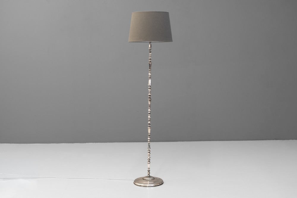 A tall silvered metal floor lamp featuring a detailed knopped column stem, a circular base, and a tapered grey fabric lampshade. View II