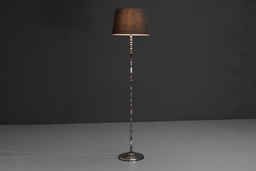 A tall silvered metal floor lamp featuring a detailed knopped column stem, a circular base, and a tapered grey fabric lampshade. View III