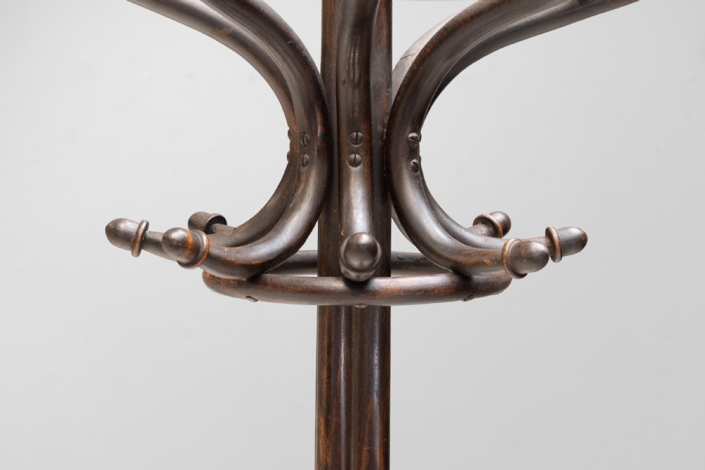 A tall dark brown bentwood coat stand with multiple S-curved hooks at the top, a slender central shaft, an integrated umbrella ring, and four curved splayed legs. View VI