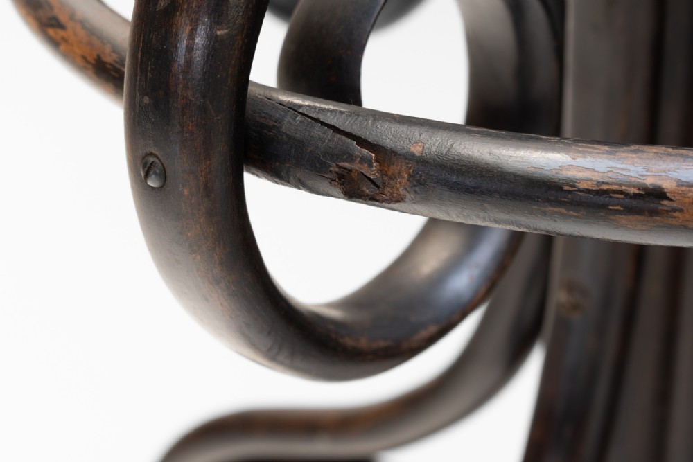 A tall dark brown bentwood coat stand with multiple S-curved hooks at the top, a slender central shaft, an integrated umbrella ring, and four curved splayed legs. View IX