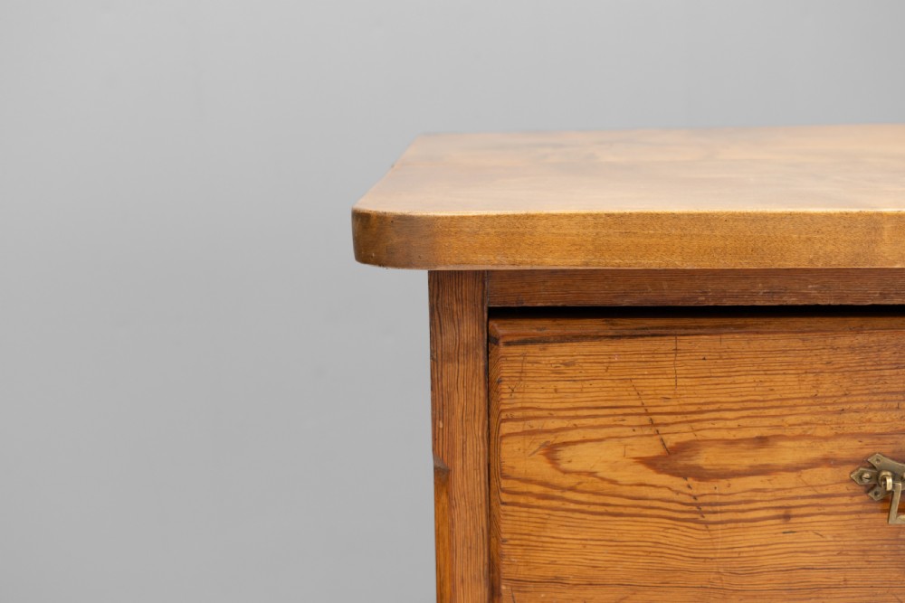 A warm brown pine sideboard featuring a central arched cupboard door flanked by six drawers with brass handles on a solid plinth base. View VIII