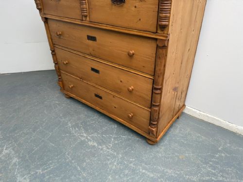 fig 2. A large antique waxed pine chest of drawers featuring two small upper drawers over three full-width drawers with turned side columns.