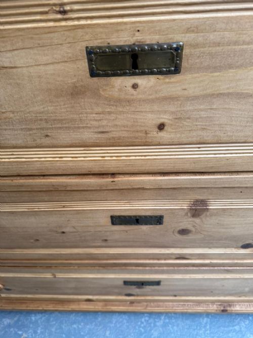 fig 1. A three-drawer waxed pine chest featuring side columns with carved capitals, turned wooden knobs, and inset brass keyhole escutcheons.