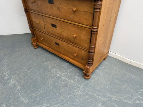 fig 1. An antique waxed pine chest of drawers featuring turned side columns, two upper drawers, and three long lower drawers with wooden knobs.