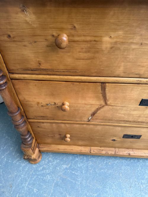 fig 2. An antique waxed pine chest of drawers featuring turned side columns, two upper drawers, and three long lower drawers with wooden knobs.
