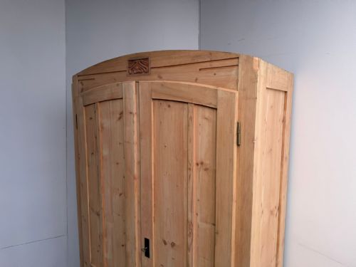 fig 1. A tall stripped pine double-door cupboard featuring an arched top rail with a central carved Art Nouveau motif and panelled doors.