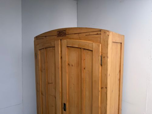 fig 1. A tall freestanding antique waxed pine storage cupboard with panelled double doors, an arched top rail, and a central Art Nouveau carved detail.