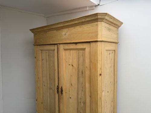 fig 1. An early Georgian pine knockdown wardrobe with a prominent moulded cornice, two flat-panelled doors, and a sturdy plinth base.