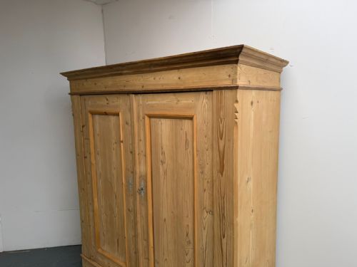 fig 2. A low two-door natural pine wardrobe featuring twin moulded door panels, a prominent cornice, and a plinth base.