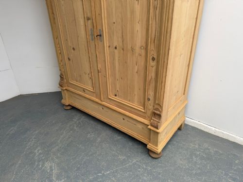 fig 1. A Victorian stripped pine two-door wardrobe featuring a knockdown construction, carved corbels, panelled doors, metal escutcheons, and bun feet.