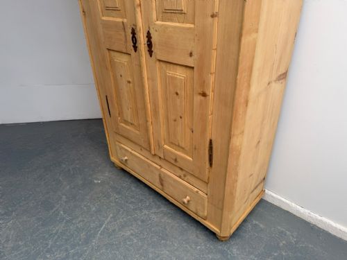 fig 1. A Georgian natural stripped pine wardrobe featuring double panelled doors, iron hardware, and a lower drawer.