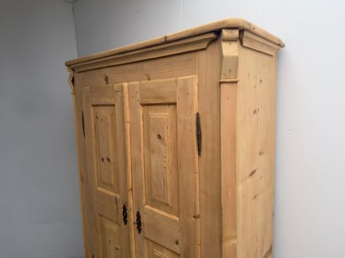 fig 2. A Georgian natural stripped pine wardrobe featuring double panelled doors, iron hardware, and a lower drawer.