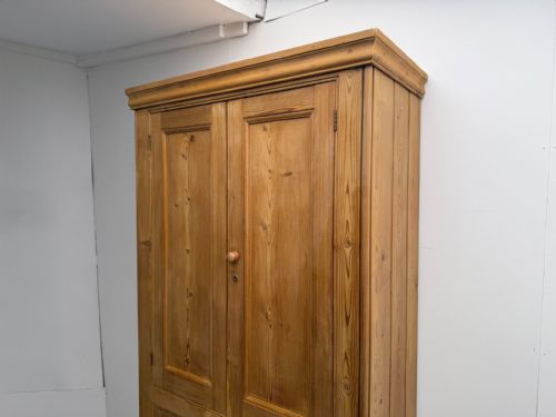 fig 1. A tall Victorian pine storage cupboard with four panelled doors, wooden knobs, and a waxed finish against a white background.
